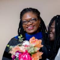 Faculty awardee smiling with a friend holding flowers